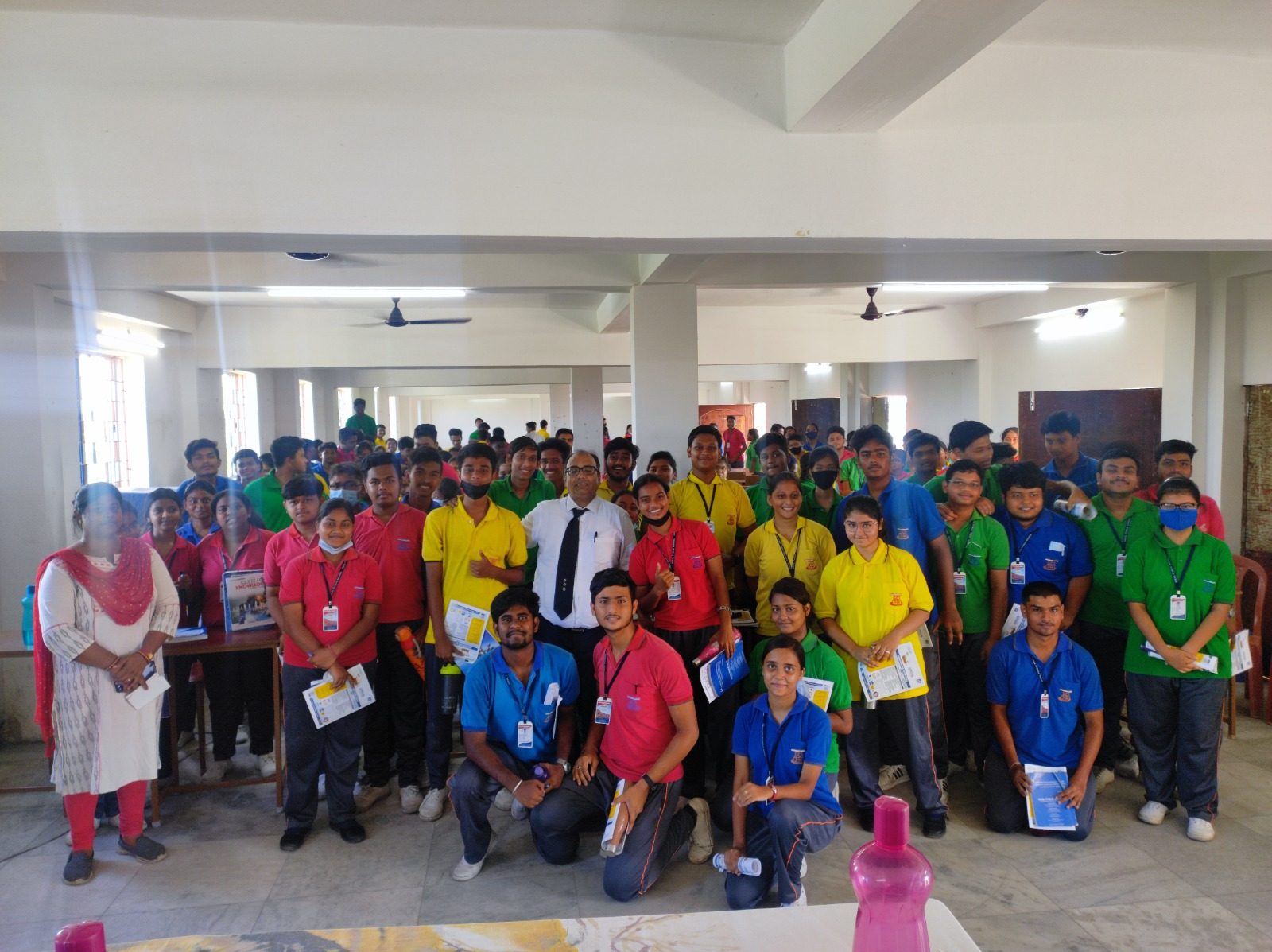 Students in coloured polo shirts gathered around a speaker