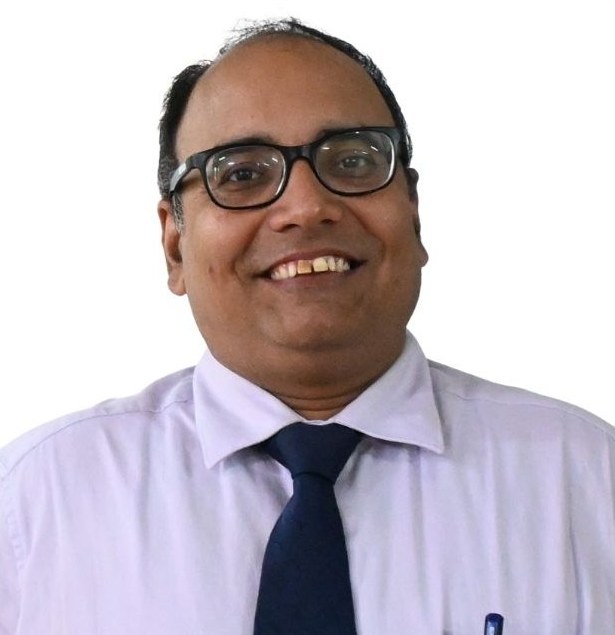 Portrait of Vijay Upadhyay, smiling, wearing glasses, a lavender shirt and a navy tie